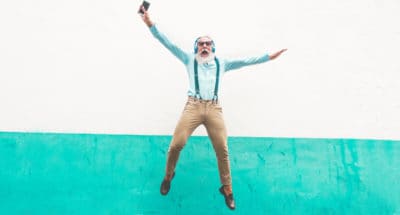 Senior crazy man jumping and listening music outdoor - Happy mature male celebrating and dancing outside - Joyful elderly lifestyle concept - Focus on him