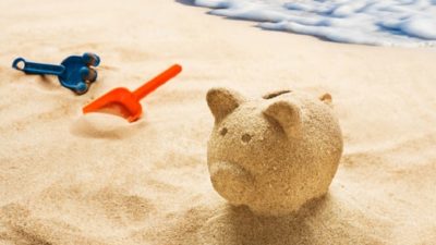 Piggy bank made from sand on beach