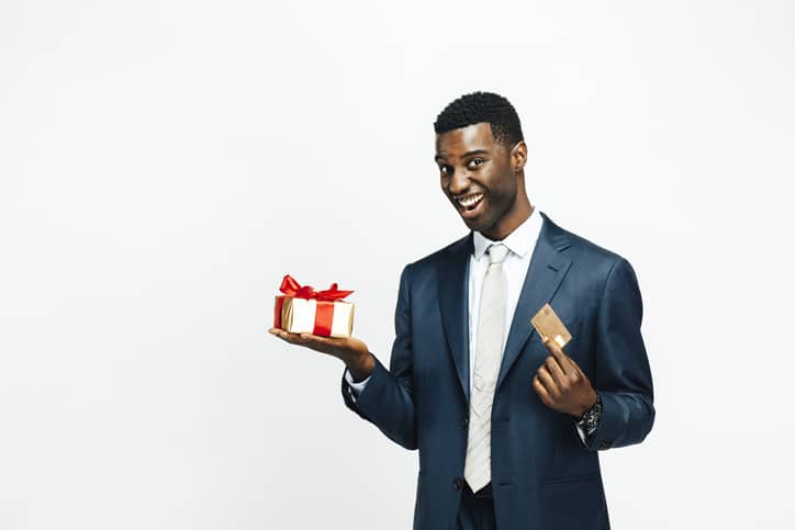 Smiling man holding beautiful gift and a golden credit card