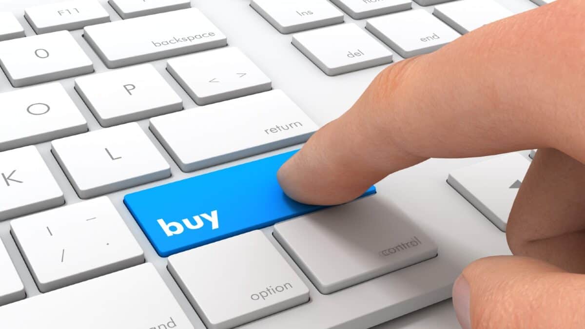 Finger clicking a button marked 'Buy' on a keyboard