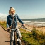 Woman riding her old fashioned bicycle along the Beach Esplanade at Aberdeen, Scotland.